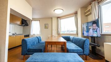 A compact living space with a kitchenette, a dining table, a sofa, and a television.