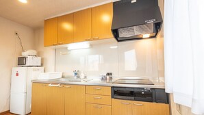 Une cuisine de taille réduite, dotée de meubles en bois, d’un four à micro-ondes, d’un lave-vaisselle et d’une cuisinière.