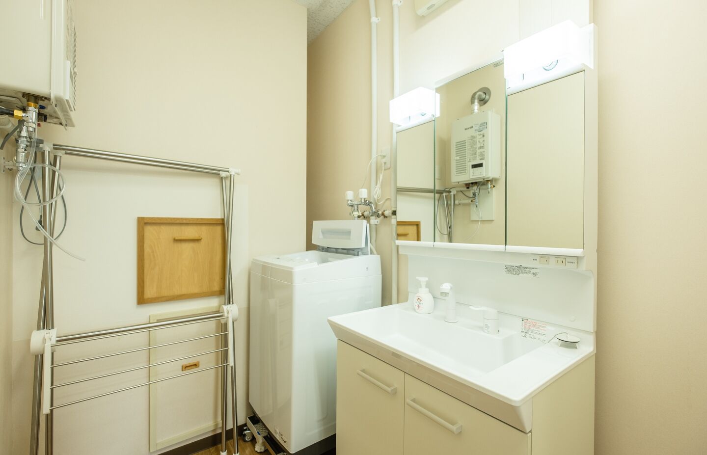 A clinical, functional bathroom with a white sink, mirror, and a white washing machine.