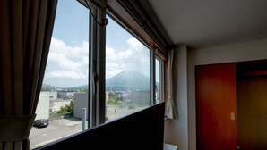 Une chambre d’hôtel dotée d’une grande fenêtre donnant sur une montagne et un parking.