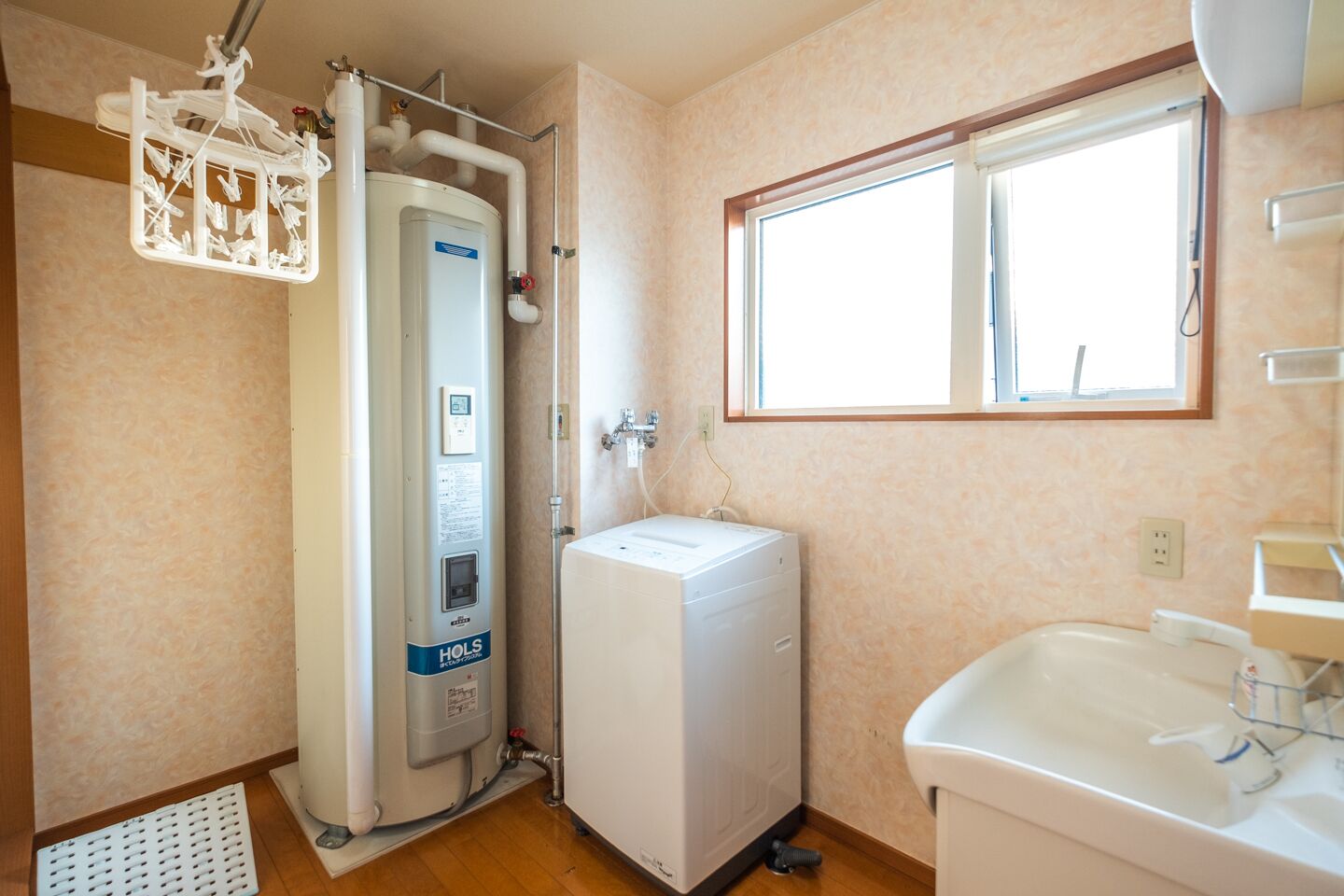 Ein kleines Badezimmer mit integriertem Wasserboiler, einer Waschmaschine und einem Waschbecken.