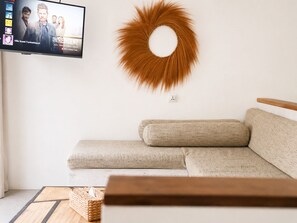 Una sala de estar con un sofá moderno, una decoración circular en la pared y un televisor mostrando un programa.