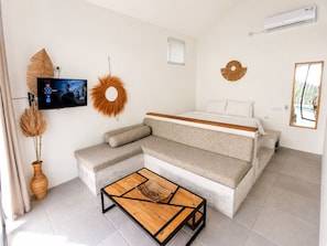 A modern bedroom with a sofa bed, a wooden coffee table, a TV, and decorative wall art.