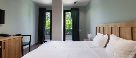 Una habitación de hotel con una cama grande, un cabecero de madera, un escritorio con una silla y un televisor en la pared.