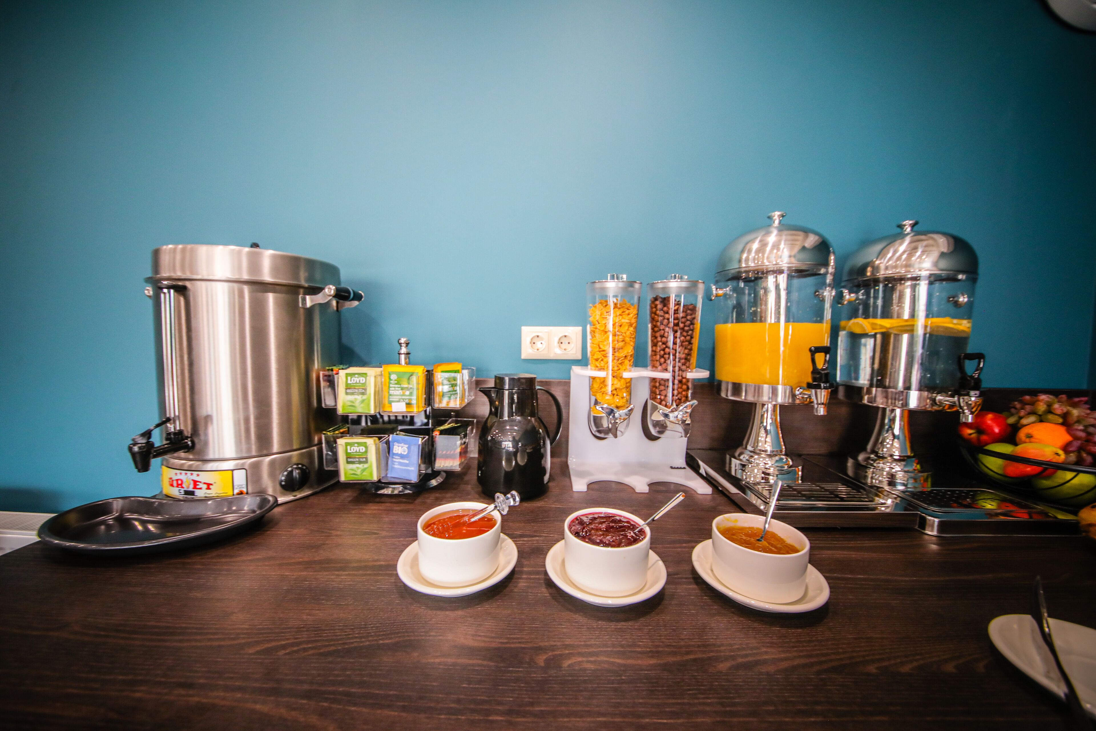 Montaje de un bufé de desayuno con cafetera, dispensadores de zumo y fruteros.