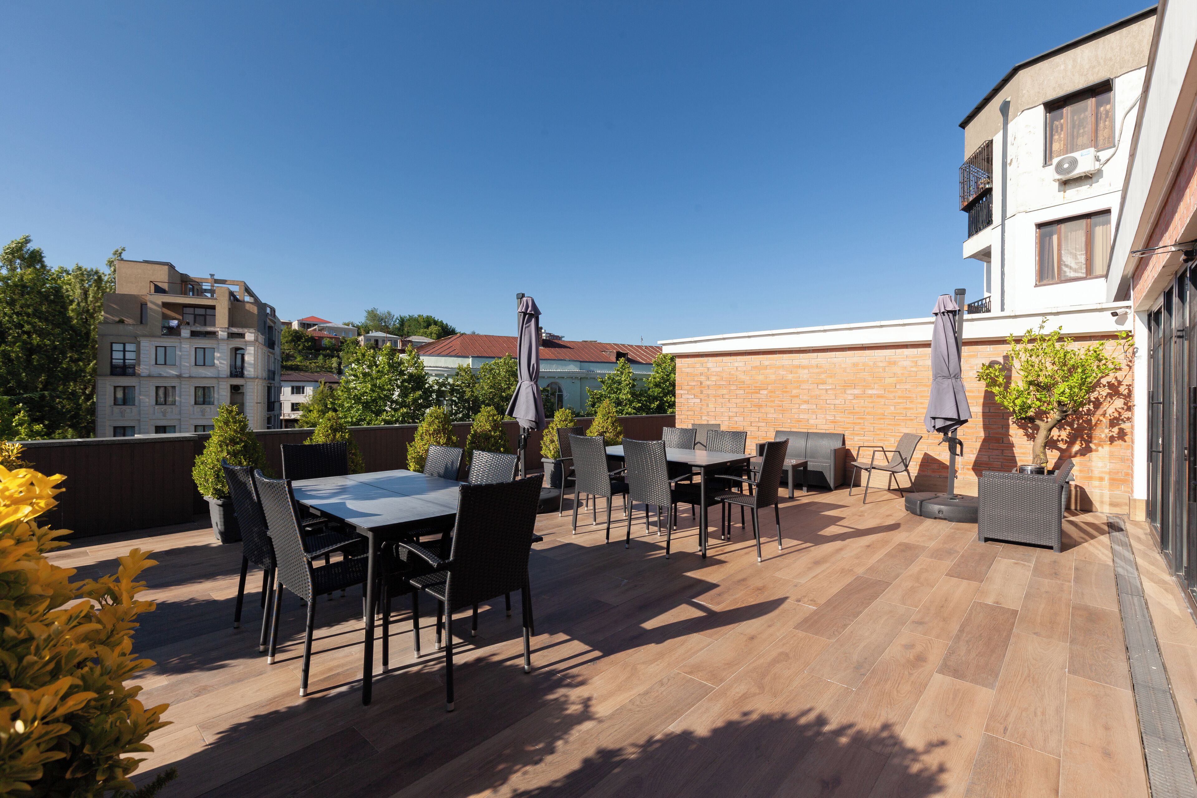 An outdoor patio area with multiple tables and chairs, surrounded by brick walls and potted plants.
