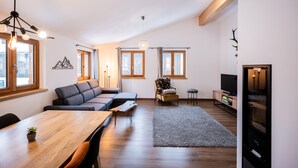 Un soggiorno moderno con un tavolo da pranzo in legno, un divano grigio, un tavolino e un mobile TV.