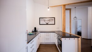 Una cucina moderna con mobili bianchi, un piano di lavoro nero e travi in legno.