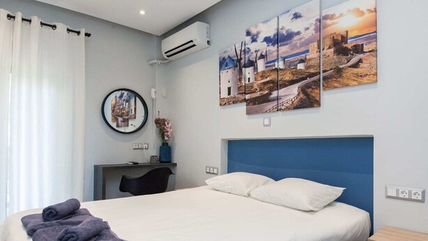 Een hotelkamer met een bed, een bureau en een wandairconditioner.
