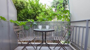 Een klein balkon buiten met een metalen tafel en twee stoelen, omringd door een metalen hek.