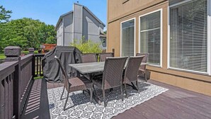 Eine Außenpatio mit Tisch und Stühlen, einem Grill und Blick auf ein Nachbargebäude.
