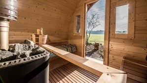 Un cuarto de sauna con paredes de madera, un banco y un calentador de sauna.