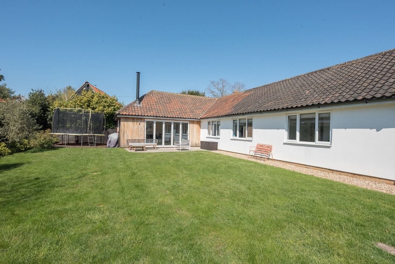 Een gelijkvloers huis met een pannendak, een overdekt terras en een verzorgd gazon.