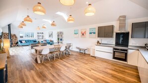 A spacious living area with a wooden floor, a dining table, and a kitchen with modern appliances. - Springfield, Westleton (Saxmundham)