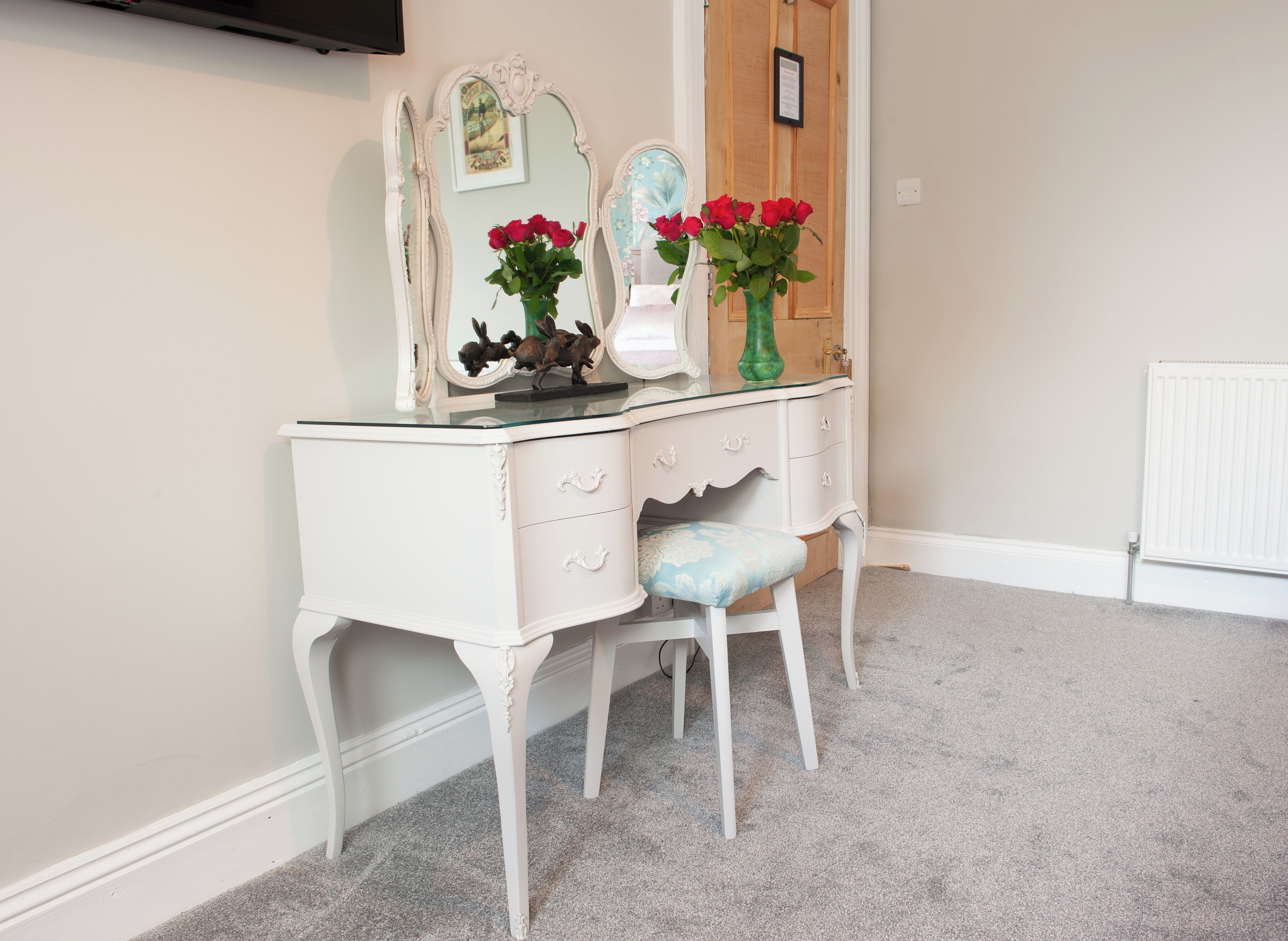 A white vanity with a mirror, two drawers, and a stool.