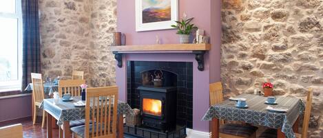 A dining area with a stone wall, a fireplace, and wooden furniture.