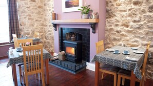 A cozy dining area with a stone wall, a fireplace, and a table set for two.