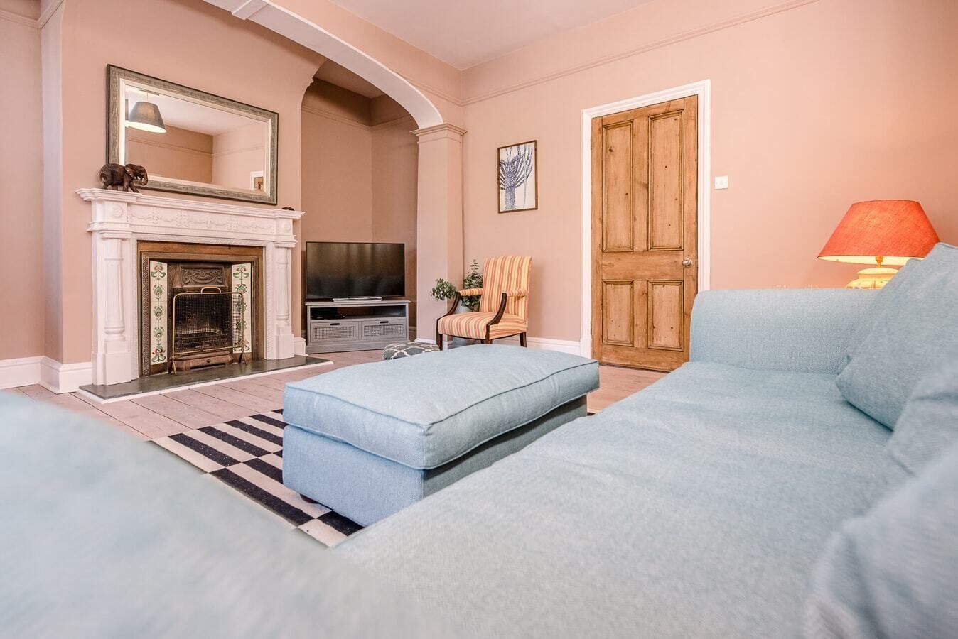 Una sala de estar con chimenea, televisor, un sillón a rayas y una puerta de madera.