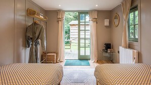 Une chambre avec deux lits, un radiateur, une table avec une bouilloire et une vue sur l’extérieur.