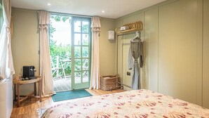A bedroom with a bed, a small table with a bag, a robe, and a shower area. - Feather Lodge, Toad Hall, Wangford (Wangford)