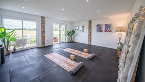 A spacious room with a large sliding glass door leading to a balcony, a fireplace, and a view of the outdoors. - Feather Lodge, Toad Hall, Wangford (Wangford)