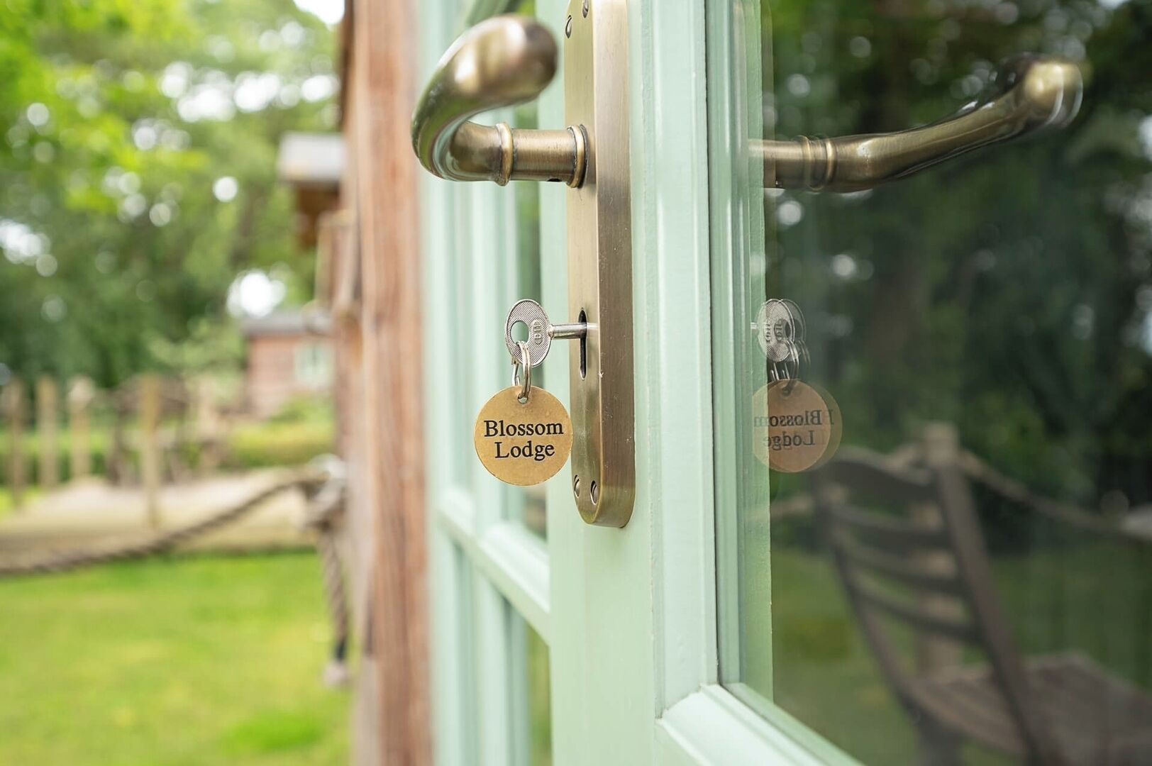 A door with a brass handle and a keyhole, and a key with 'Blossom Lodge' engraved on it.