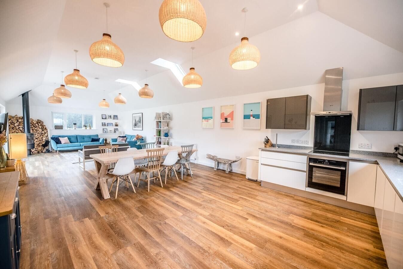 A spacious living area with a wooden floor, a dining table, and a kitchen with modern appliances.