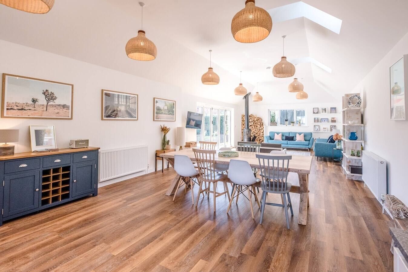 A spacious living area with a dining table, chairs, and a blue sofa.