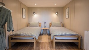 Une chambre avec deux lits jumeaux, une petite table ronde et un peignoir accroché sur le côté gauche.