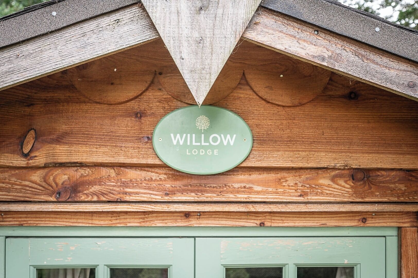 A green sign with 'WILLOW LODGE' on a wooden structure.