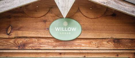 A green sign with 'WILLOW LODGE' on a wooden structure.