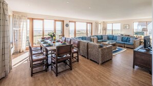 A spacious living room with a dining area, large windows, and a balcony with a view. - Fairhaven, Thorpeness (Thorpeness)