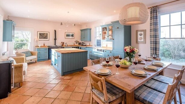 A spacious kitchen with blue cabinets, a central island, and a dining area set for six.