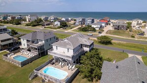 A residential area with a large house featuring a swimming pool, a covered deck, and a view of the ocean. - 5813- Crowe's Nest, South Nags Head with Private Pool, Pool Table and Ocean View...Family Fun! (Nags Head)