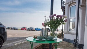 A table with tea set and flowers on a balcony overlooking a parking area.
