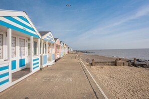 Une rangée de cabanes de plage, avec un sentier sablonneux menant à la plage.