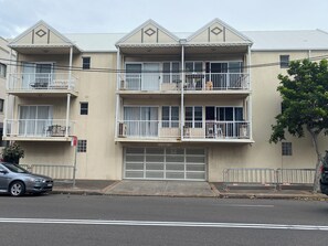 A multi-story residential building with balconies, a garage, and a street view.