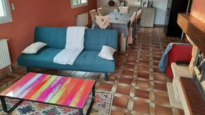 Ein gemütliches Wohnzimmer mit einer Couch, einem farbenfrohen Tisch mit Streifenmuster und einem Fliesenboden.