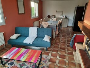 Uma sala de estar aconchegante com um sofá, uma mesa listrada e colorida, e um chão de azulejos.