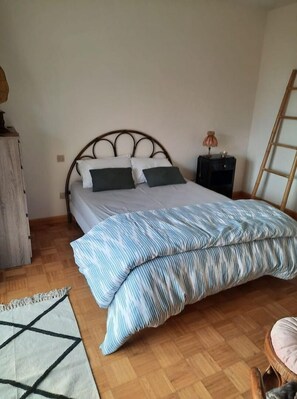 A bedroom with a bed, a nightstand, a wooden dresser, and a chair. - Gîte Les Petits Choux (Saint-Quentin-la-Motte-Croix-au-Bailly)