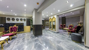 Un'area reception con pavimento in marmo, arredi dorati e viola e una scrivania per gli ospiti.