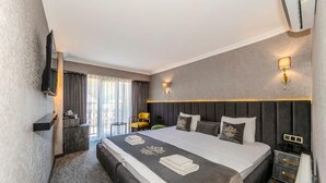 Una camera d'albergo con un grande letto, un comodino, una sedia, una televisione e una finestra con tende.