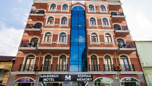 A hotel with a prominent blue glass facade, multiple balconies, and a sign indicating it offers memory services. - Memory Hotel Batumi (Batumi)