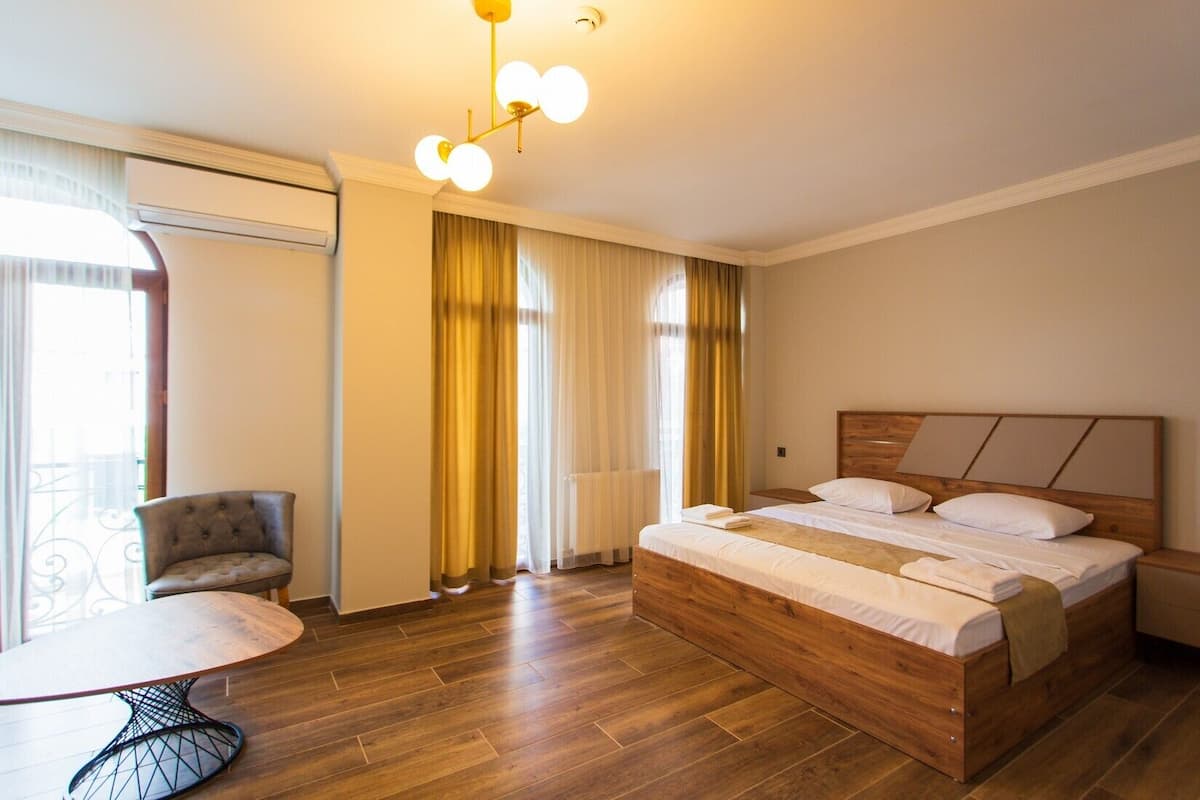 A hotel room with a wooden bed, a round table, and a chair.