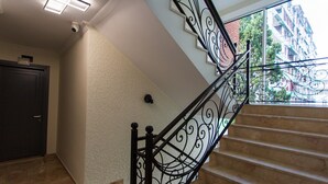 A staircase with ornate black railings, beige walls, and a view of a building outside. - Memory Hotel Batumi (Batumi)