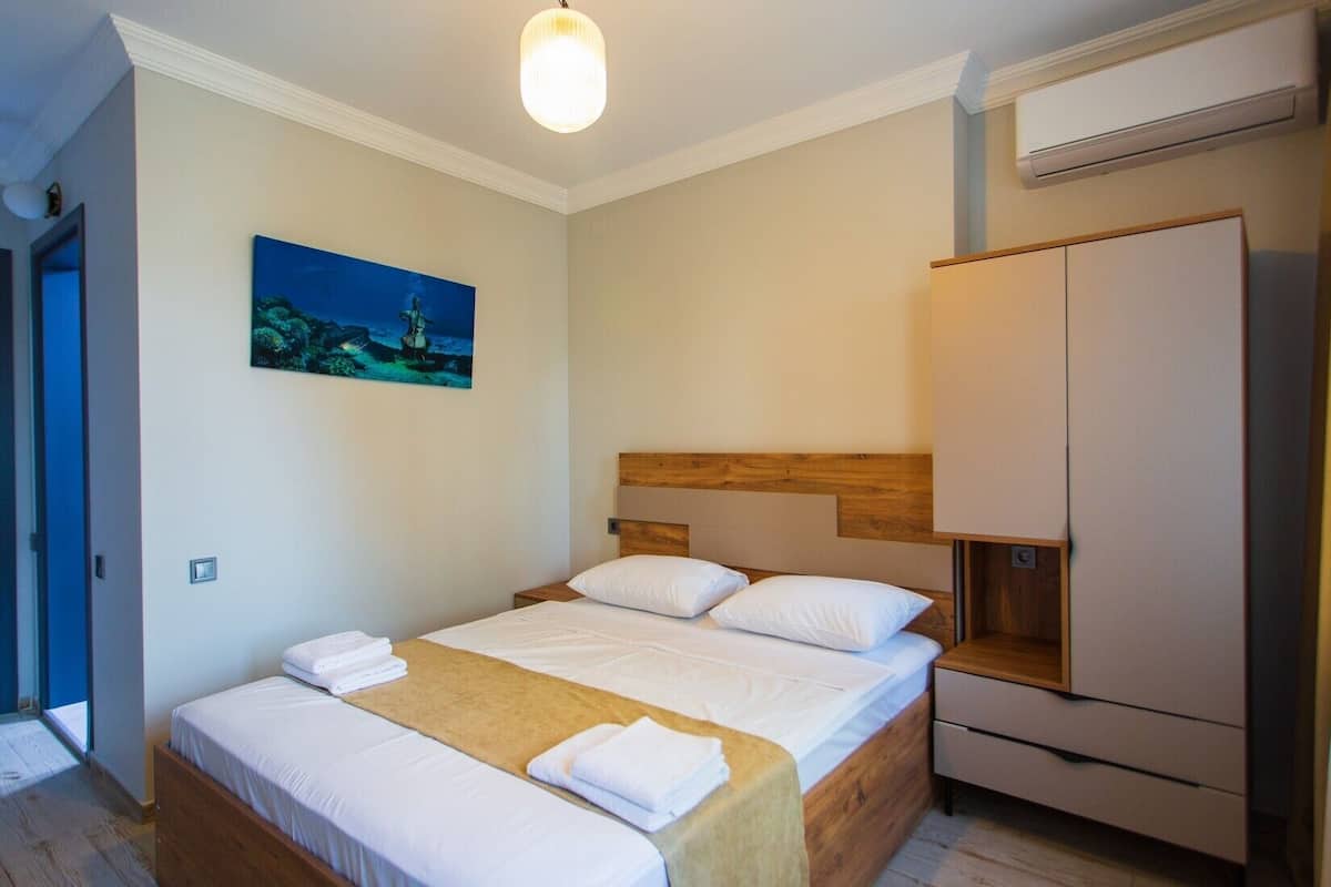 A bedroom with a bed, a nightstand, a wardrobe, and a painting on the wall.