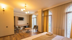 A hotel room with a bed, a desk, two chairs, a TV, and a window with curtains. - Memory Hotel Batumi (Batumi)