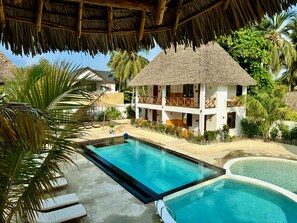 A resort with a large pool, thatched-roof buildings, and lush greenery. - Mayai Ocean Resort (Bwejuu)