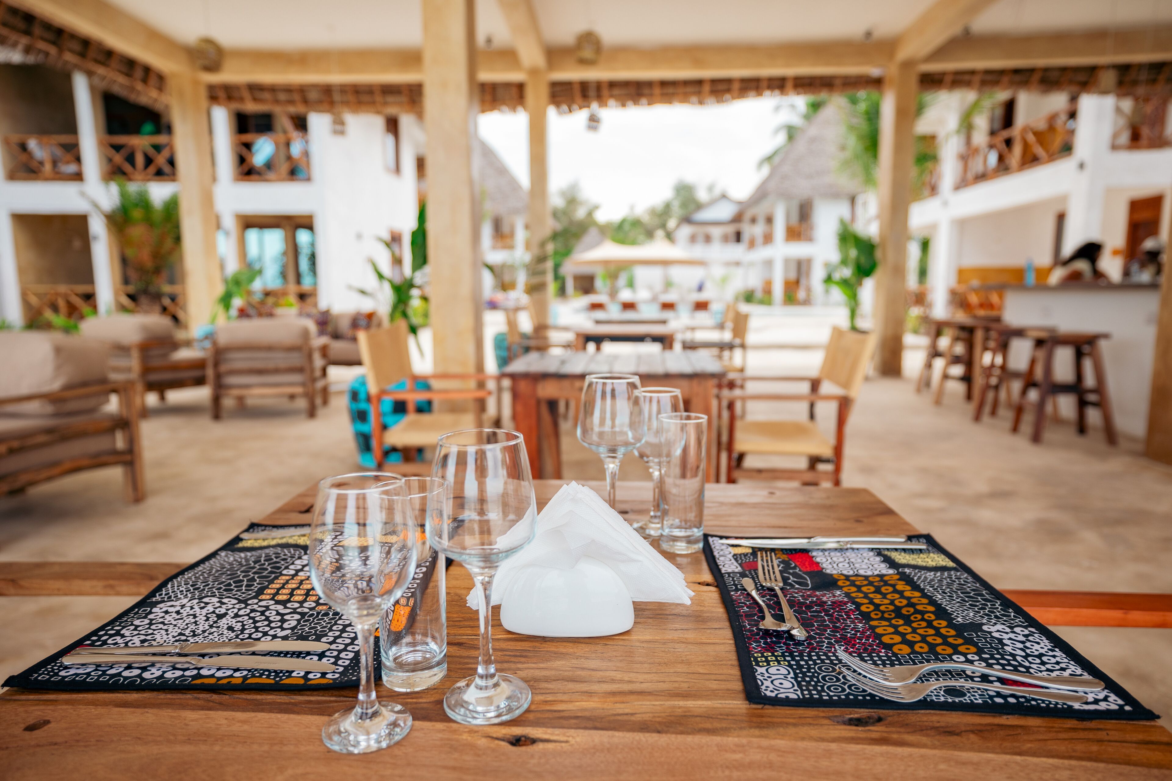 A dining area with tables set for a meal, featuring clear glassware and a napkin.