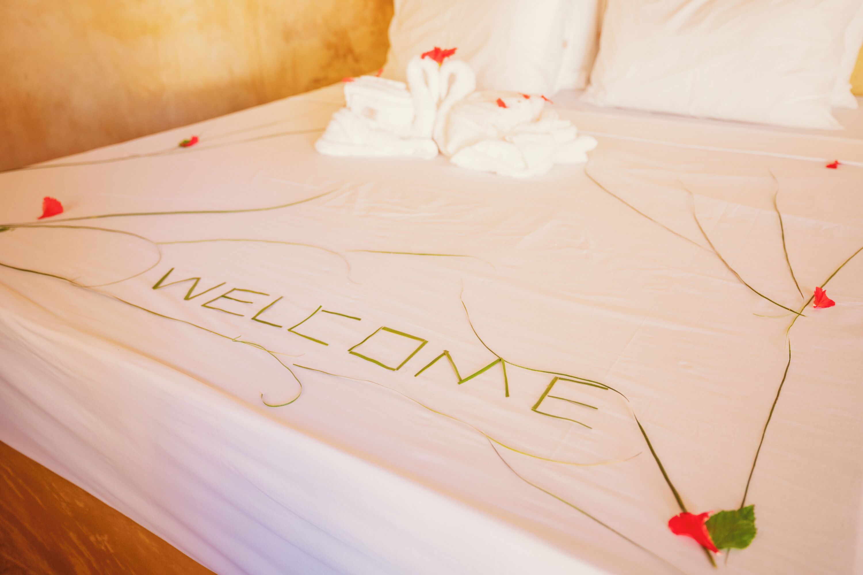 A bed with a "WELCOME" sign made of flowers and a swan decoration.